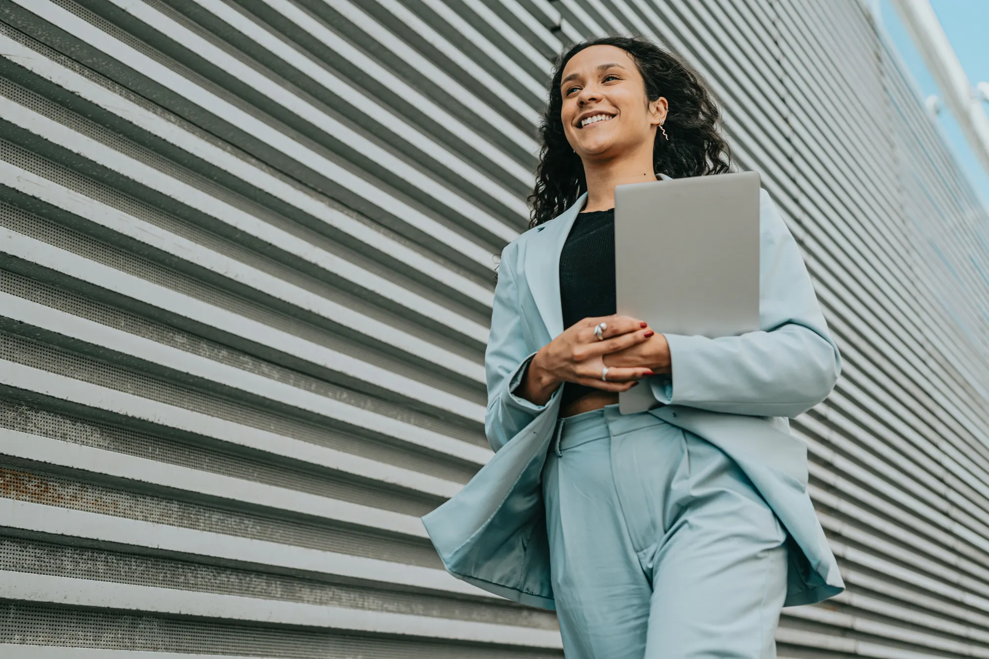 A professional walking into work with a laptop